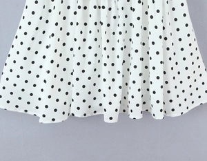Detail eines weißen Polka-Dot-Kleidsaums aus leichtem Webstoff mit elegantem Faltenwurf