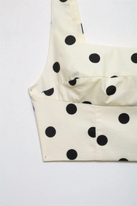 Macro detail showing woven cotton fabric with large black polka dots on cream crop top