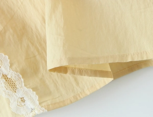 Detail of light yellow dress featuring delicate white lace trim and cotton-linen texture