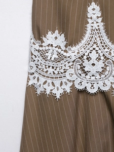Detail of brown striped fabric with white floral lace embroidery on a summer dress