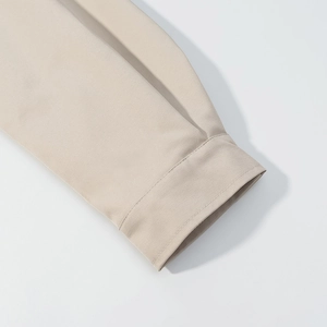 Detailopname van beige jas mouw met fijne stiksels en gladde stoftextuur van dichtbij