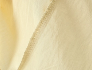 Detail shot of meticulous overlock stitching on beige lace dress inner seams