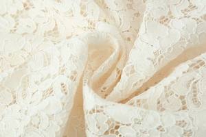 Primer plano de tela de encaje blanco crema con detalles florales de ganchillo calados