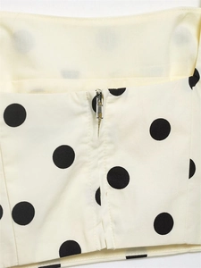 Detailed close-up of cream polka dot fabric with premium silver metal zipper hardware