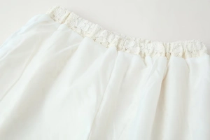 Detail of white lace elastic waistband and lightweight fabric texture on summer pants