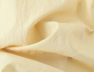 Close-up of pale yellow breathable fabric with natural crinkle texture for summer dress