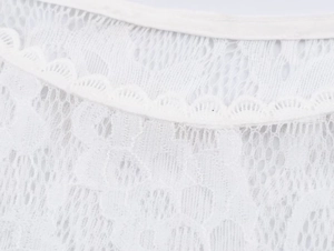 Close-up of white floral lace fabric with delicate mesh and scalloped edges for dress