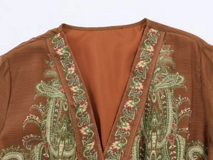 Close-up of V-neckline with vintage paisley embroidery and woven texture fabric