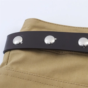 Détail de la jupe en toile kaki avec ceinture en cuir marron et rivets en métal argenté