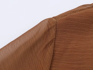 Macro detail of brown pleated chiffon fabric with high-quality stitching and texture