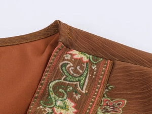 Detailed macro view of bohemian embroidery and linen texture on a retro brown dress