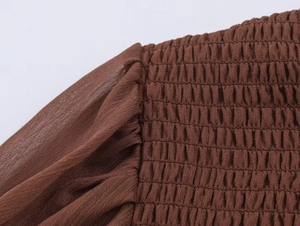 Detailed view of dark brown smocked bodice with vertical elastic shirring and gathered sleeves