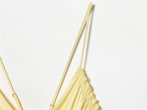 Detail of adjustable thin straps and smocked neckline on a light yellow satin dress
