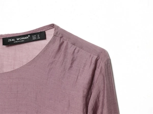 Détail de l'encolure ronde avec tissu texturé et étiquette sur ce haut pour femmes