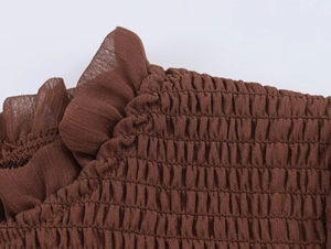 Detail of coffee smocked chiffon fabric with elegant ruffled edges and textures