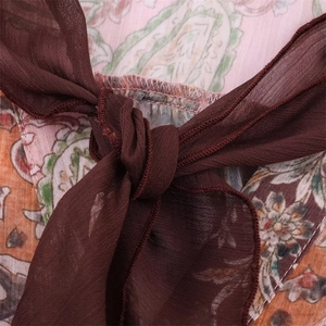Close-up of paisley floral print fabric with brown chiffon ribbon and fine pleated details