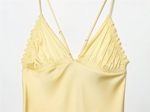 Detail of light yellow satin dress featuring delicate ruffles and thin shoulder straps