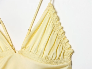 Detailed view of pale yellow satin top with ruffled edges and elastic shirring detail