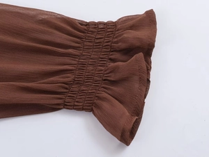 Detail of brown long sleeve cuff with elastic smocking and ruffle lace design