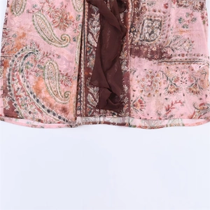 Detail of bohemian floral paisley print on light pink chiffon blouse with brown ruffles