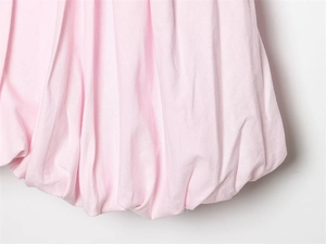Détail d'une robe rose clair avec un ourlet bulle volumineux et des plis verticaux