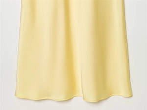 Close-up of pale yellow satin dress fabric showing premium drape and fine stitching