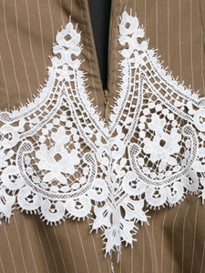 Detail of white lace embroidery on a brown striped dress with a concealed zipper