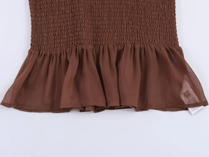 Detail of brown smocked bodice with ruffled hem and textured chiffon fabric finish