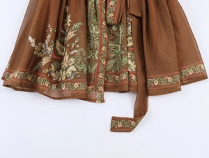 Detail view of deep brown V-neck dress featuring paisley floral prints and a matching waist tie
