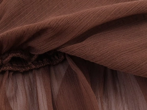 Close-up of brown crinkled chiffon fabric with elastic smocking and pleated texture