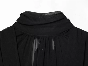 Close-up of black pleated neckline on a sheer balloon-style top with draping details