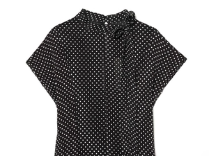 Close-up of black and white polka dot chiffon top with elegant bow tie neckline detail