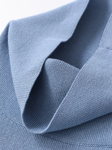 Macro shot of fine knit texture and ribbed hem on a dusty blue women's sweater