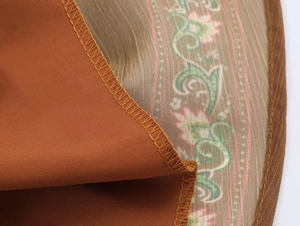 Macro shot of V-neck printed dress showing detailed seam stitching and chiffon fabric texture