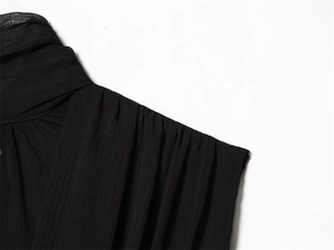 Detailed close-up of pleated black chiffon neckline and shoulder texture on women's top