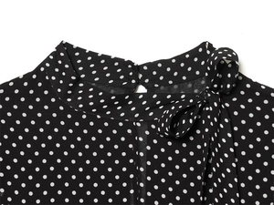 Detail of mock neck black polka dot top showing back button closure and tie-bow