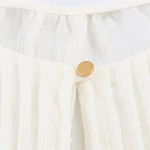 Detailed macro view of white pleated chiffon fabric with an elegant gold metal button