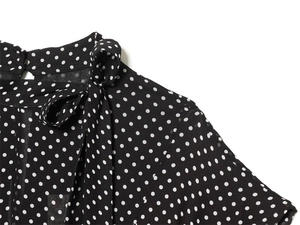 Detail of a chic bow tie neckline on a black polka dot dress with sheer fabric