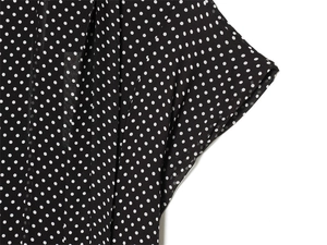 Detail of black and white polka dot chiffon dress showing collar cut and sleeve draping