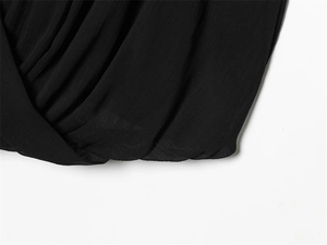 Detail of black pleated chiffon fabric featuring elegant cross V-neck draping texture
