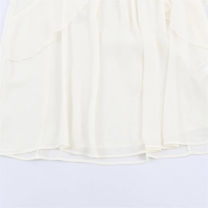 Detail view of white layered ruffle hem on lightweight chiffon shirt for women
