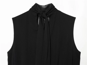 Close-up of elegant black sleeveless top showing tie-neck detail and light chiffon texture
