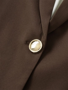 Detailansicht eines zweifarbigen Gold-Silber-Knopfes an einem braunen Freizeit-Blazer