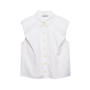Detail view of the textured seersucker fabric and ruffled shoulder design on a white shirt