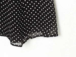 Close-up of black chiffon dress fabric with white polka dots and delicate hemline
