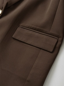 Detail eines dunkelbraunen Blazers mit seitlicher Pattentasche und goldenem Metallknopf