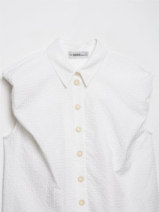 Detail view of white sleeveless shirt featuring waffle texture and classic collar buttoning