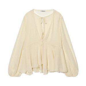 Detail of V-neckline with delicate ties and layered ruffles on a cream long-sleeved blouse
