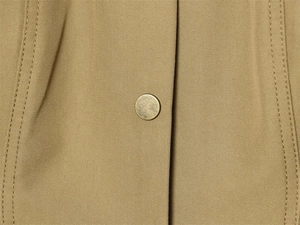 Close-up of khaki twill fabric with vintage gold metal snap button and double stitching