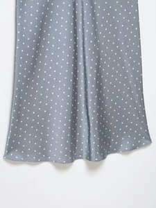 Dettaglio ravvicinato del tessuto in raso blu-grigio a pois bianchi e drappeggio elegante